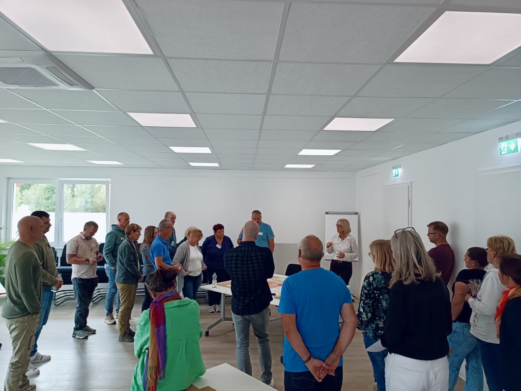 Zu sehen sind eine Gruppe an menschen die zusammen an einer Moderationswand stehen.