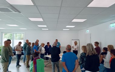 Zu sehen sind eine Gruppe an menschen die zusammen an einer Moderationswand stehen.